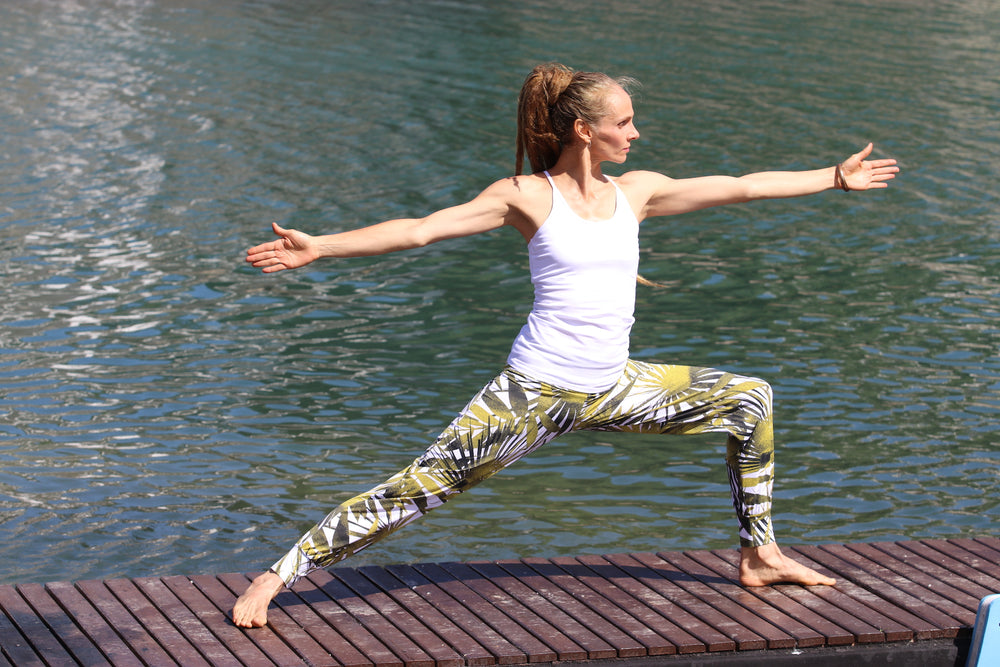 Lady Practising Warrior 2 Pose On A Lake Boardwalk